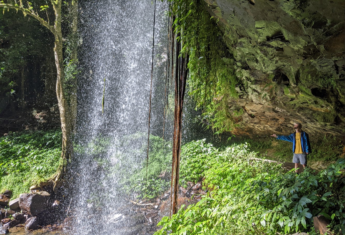 A man standing near a majestic waterfall